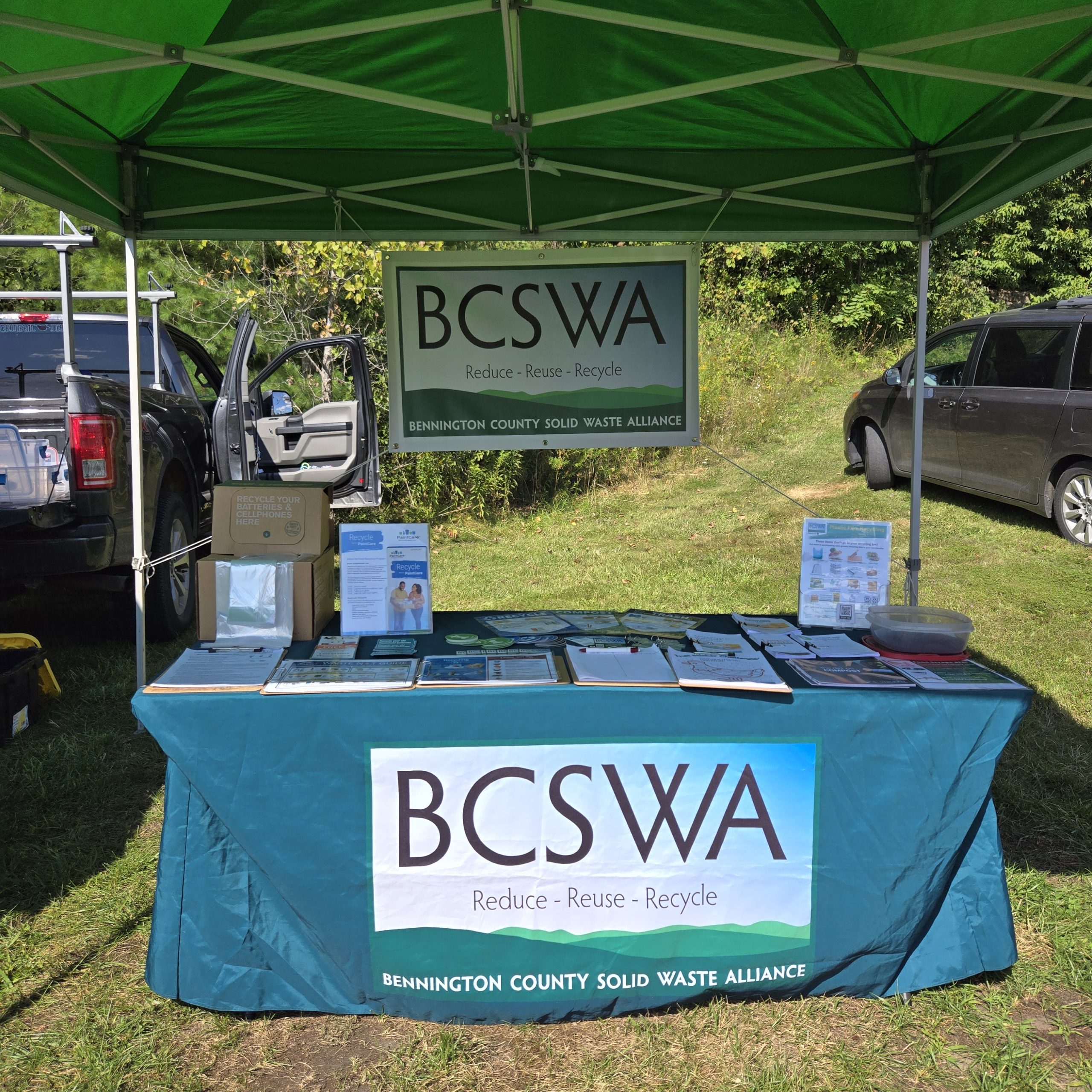A display table outdoors under a canopy with printed materials